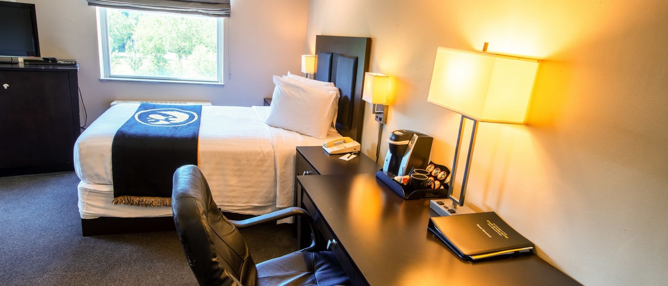 A leather office chair and black desk next to a bed in a hotel room